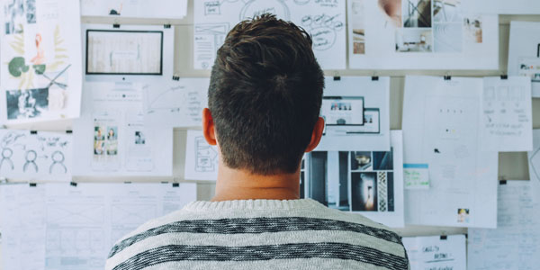 man standing in front of bulletin board of options