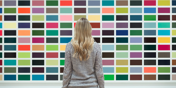 A woman with long, blonde hair, standing in front of a wall covered in rectangular colour samples.
