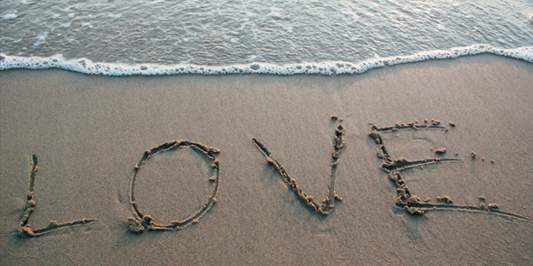The word love written on a beach as a wave rolls in