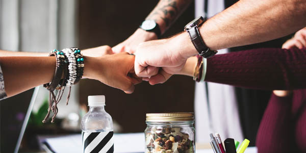 A group of people fist-bump at a table.