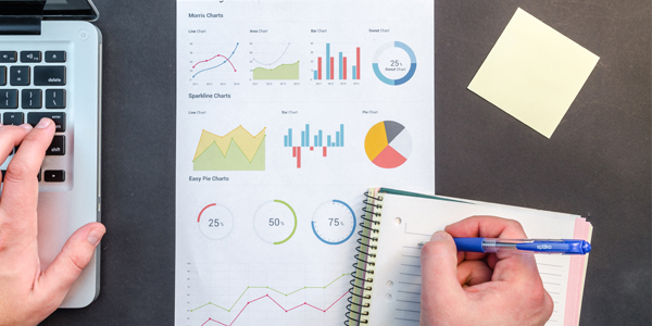 a hand taking notes from a printout of various graphs