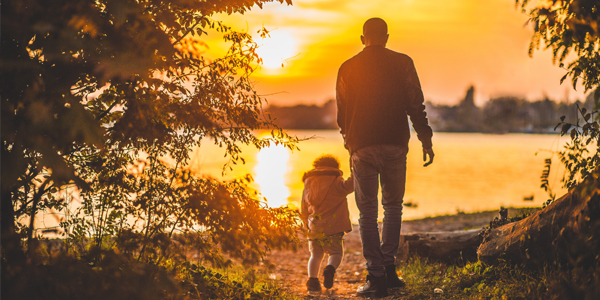father walking with child at sunset
