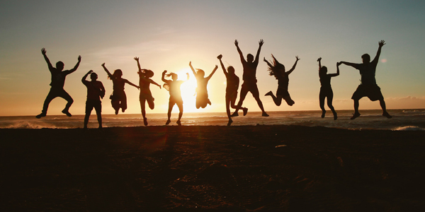 people jumping on a beach at sunset