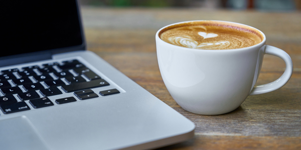 coffee cup beside a computer